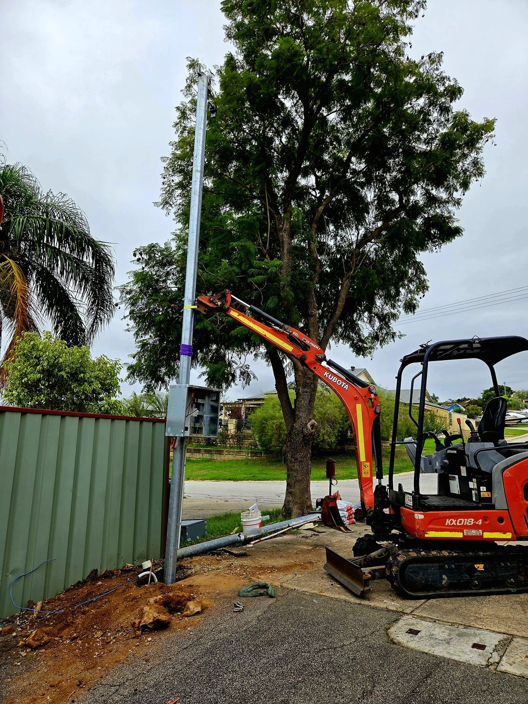 Mini excavator installing a power pole
